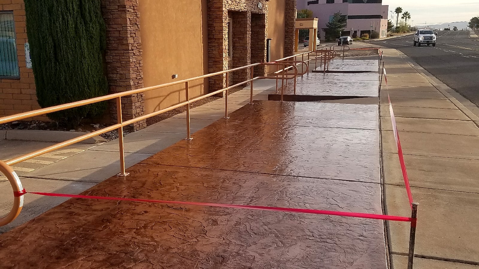 Stamped and colored concrete walkway beside a building ramp