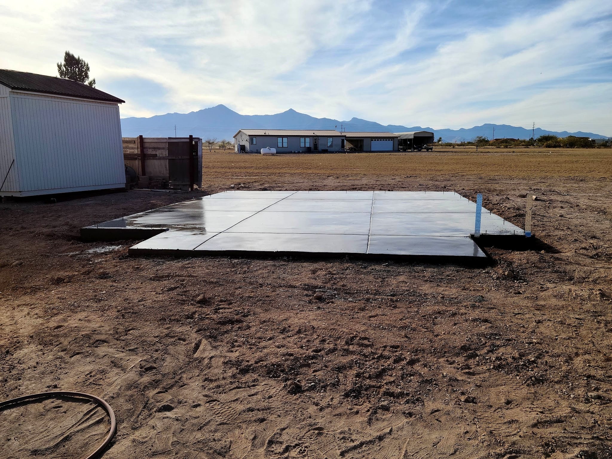 New concrete pad on open desert ground with mountains behind