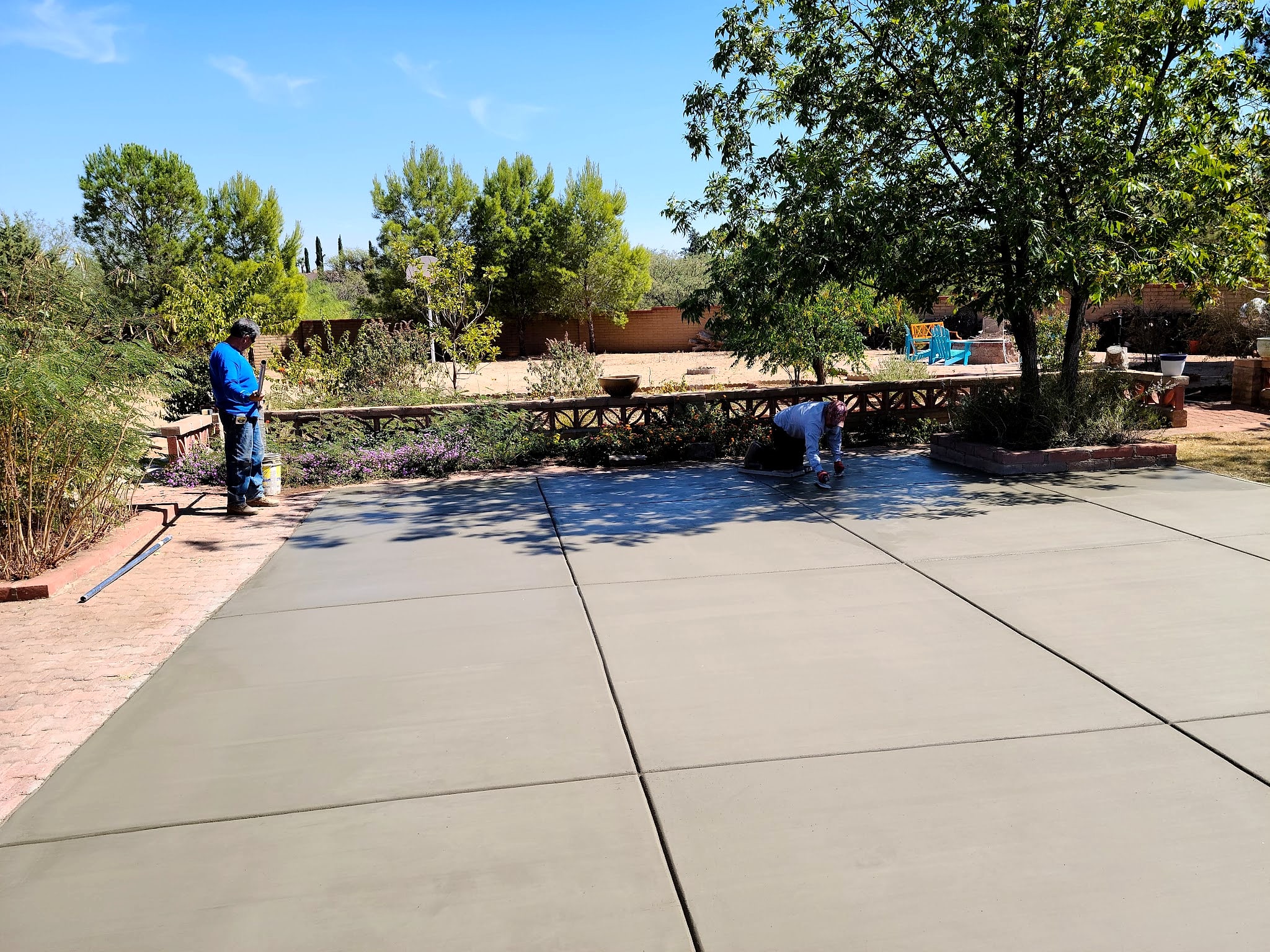 Large patio slab with control joints beside a garden