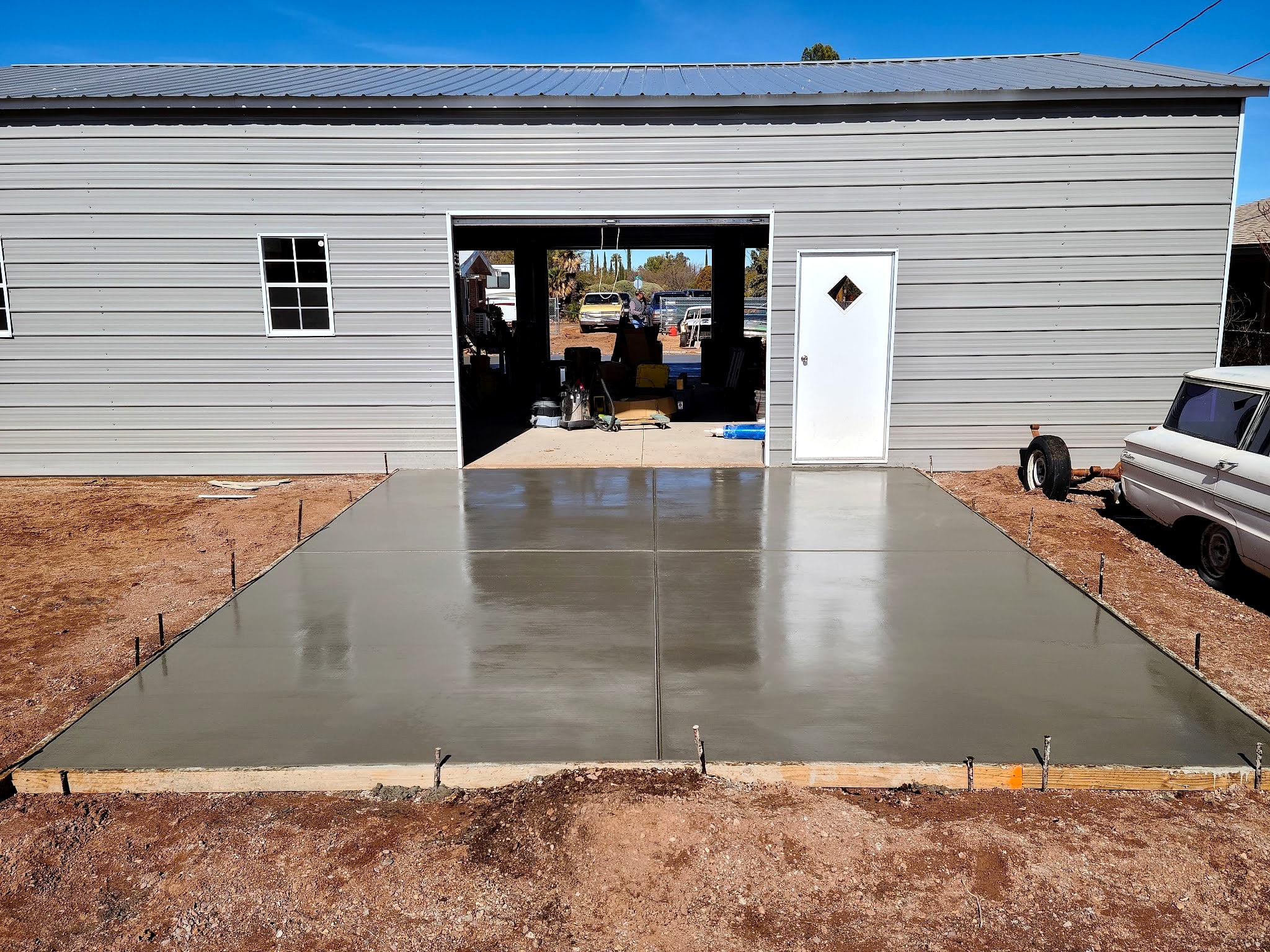Fresh slab poured in front of a metal building with its door open